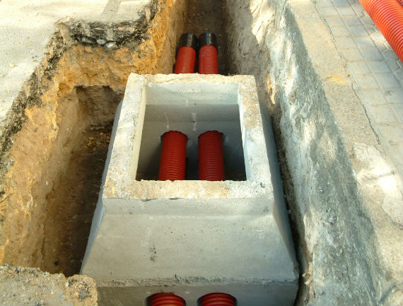 Work on an open pit in the ground showing the electrical grid cables