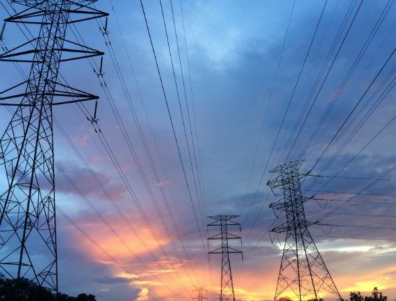 Three high-voltage electricity distribution towers in an open, uncluttered landscape