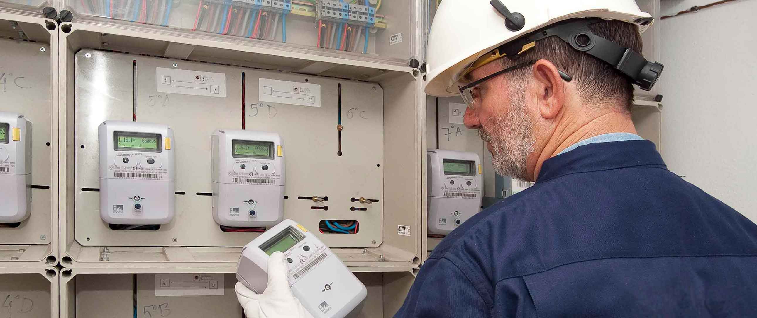 Installer in front of a central metering station with smart metering equipment in his hand
